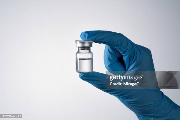 gloved hand holding sealed medical vial - medicinflaska bildbanksfoton och bilder