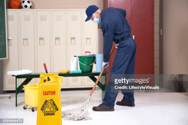 senior adult janitor mops floor in school locker room. - football face mask stock pictures, royalty-free photos & images