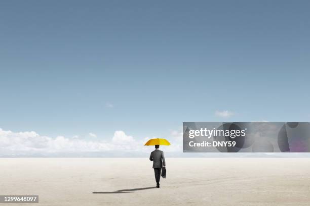 man carrying yellow umbrella on a lonely walk - yellow umbrella stock pictures, royalty-free photos & images