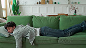 Exhausted young man came home after work flopped down on sofa