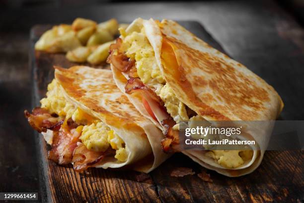 das gefaltete frühstück tortilla mit rührei, speck, tomaten und käse - tortilla stock-fotos und bilder