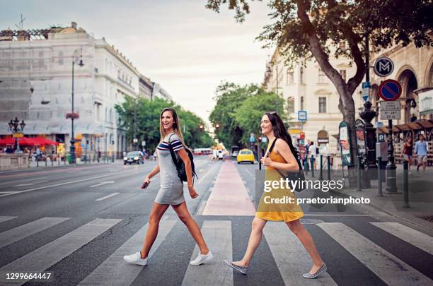 girlfriends are crossing street at the crosswalk - budapest street stock pictures, royalty-free photos & images