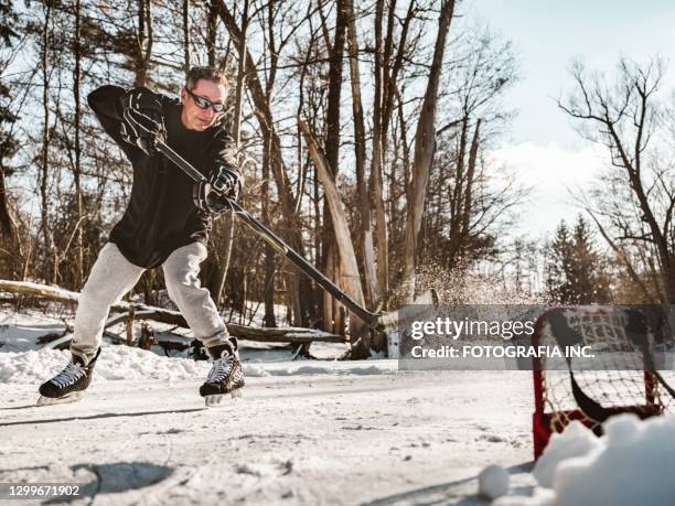 reife mann spielen hockey im freien - pond hockey stock-fotos und bilder