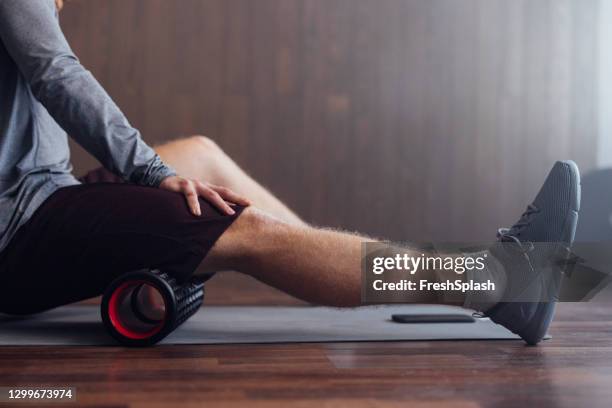 roller massage for warming up: an unrecognizable fit caucasian sportsman preparing to work out indoors - hamstring stock pictures, royalty-free photos & images
