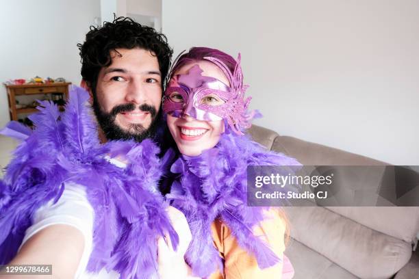 couple taking selfie celebrating carnival at home - mascara carnaval imagens e fotografias de stock