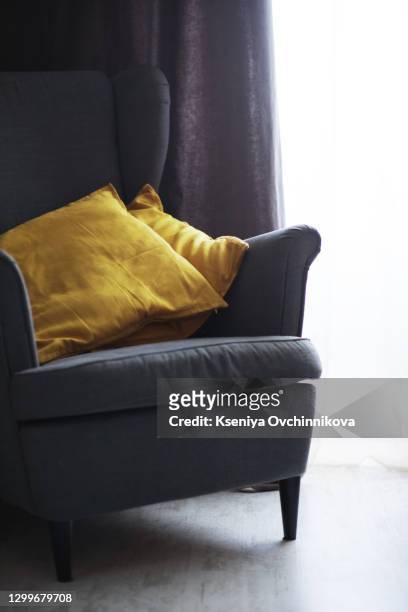 grey sofa armchair in simple setting in front of lovered windows - loveseat fotografías e imágenes de stock