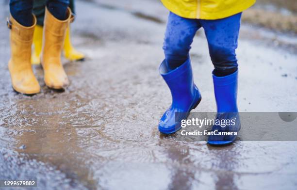 amusement dans la flaque d’eau de pluie sautant - blue boot photos et images de collection