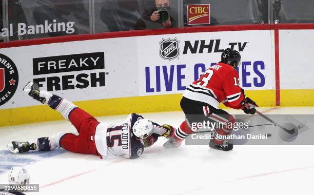 Michael Del Zotto of the Columbus Blue Jackets falls as he tries to knock the puck away from Mattias Janmark of the Chicago Blackhawks at the United...