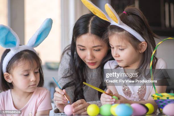 mother decorating easter eggs with her daughters - easter bunny man stock pictures, royalty-free photos & images