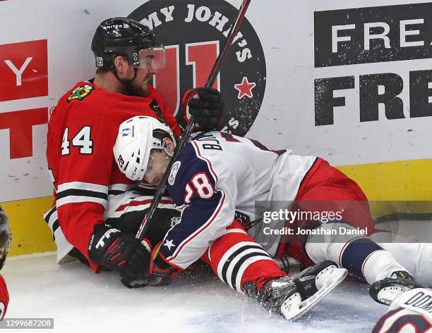 Calvin de Haan of the Chicago Blackhawks is pinned against the boards by Oliver Bjorkstrand of the Columbus Blue Jackets at the United Center on...