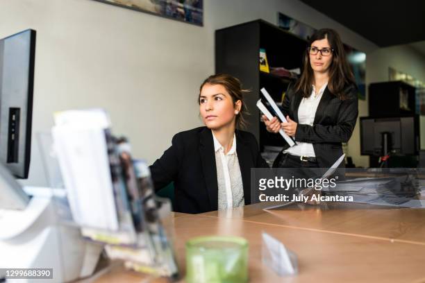 two women work in the office with documents and look at the computer - bank office clerks stock pictures, royalty-free photos & images