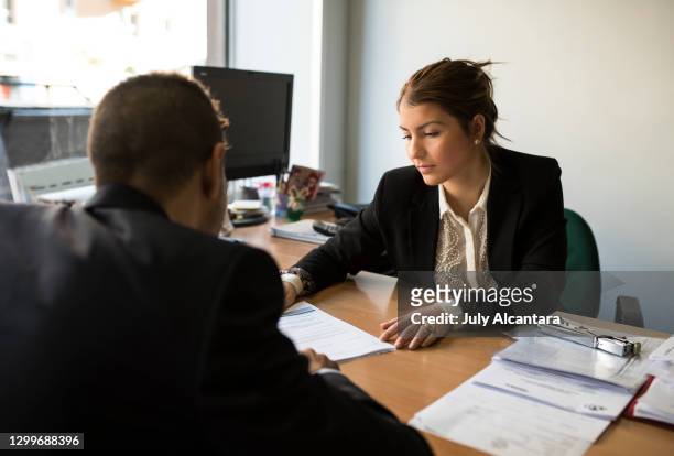 office workers looking papers in workplace - bank office clerks stock pictures, royalty-free photos & images