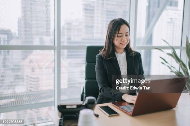 asian chinese beautiful female manager working using her laptop typing in the office - small office stock pictures, royalty-free photos & images