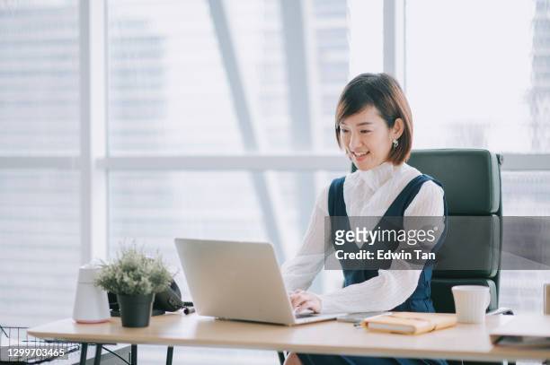 asian chinese beautiful female manager working using her laptop typing in the office - ceo desk imagens e fotografias de stock