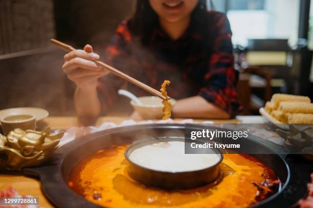 young asian woman eating chinese hot pot - hot pot dish stock pictures, royalty-free photos & images