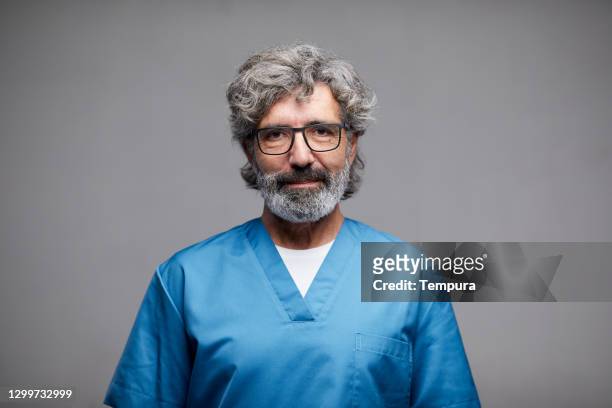 senior männliche krankenschwester porträt blick auf die kamera. - male doctor portrait stock-fotos und bilder