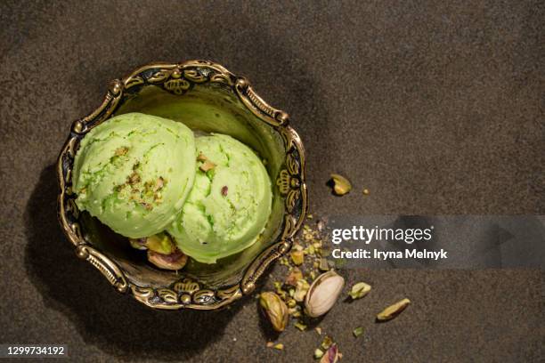 overhead shot of homemade pistachio ice cream in retro metal bowl with chopped pistachios on green brown background. top view, copy space - glace pistache photos et images de collection