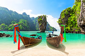 Travel photo of James Bond island with thai traditional wooden longtail boat and beautiful sand beach in Phang Nga bay, Thailand.
