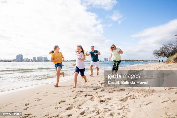 family spends time at the beach playing together on the sand - australian family time stock-fotos und bilder