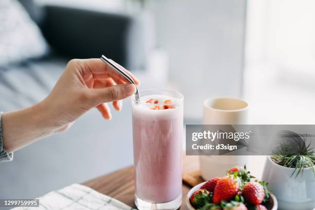 close up of young woman drinking a glass of fresh and healthy strawberry smoothie with reusable metal straw. healthy eating and healthy lifestyle - malt stockfoto's en -beelden