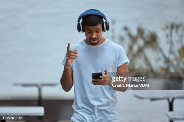 als het je beweegt, is het voor jou gemaakt. - young man listening to music on smart phone outdoors stockfoto's en -beelden