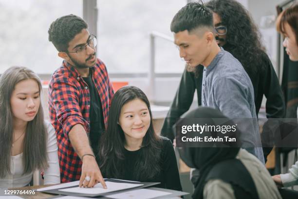 asian malay male teacher checking his students jewel design at work in college classroom - chinese tutor study stock pictures, royalty-free photos & images