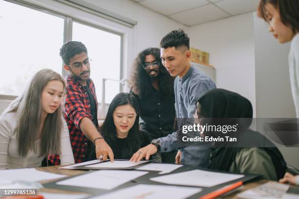 asian malay male teacher checking his students jewel design at work in college classroom - chinese tutor study stock pictures, royalty-free photos & images