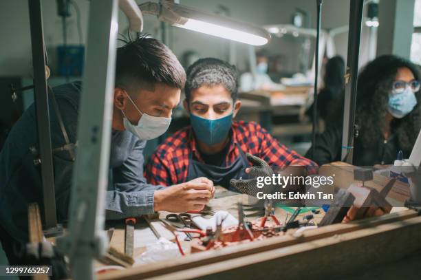 profesor malay asiático que muestra la enseñanza de su anillo de pulido de estudiantes masculino de oriente medio en la mesa de trabajo de la universidad - estudiando flexo fotografías e imágenes de stock