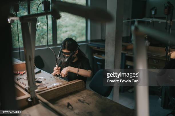 asian korean female student sewing jewelry with magnify glass at college workbench - jewellery designer stock pictures, royalty-free photos & images