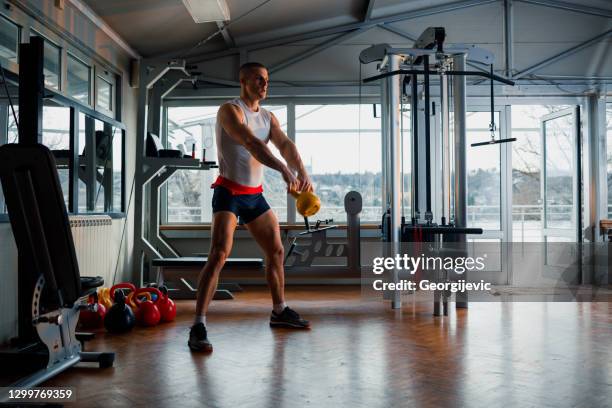 een jonge mens die met kettlebell uitoefent - triathlete stockfoto's en -beelden