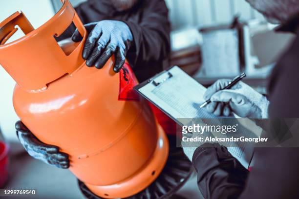 liquified gas storage workers writing down cylinder serial number - canister stock-fotos und bilder