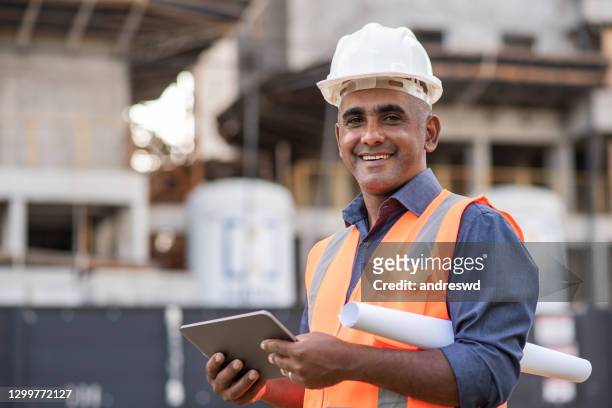 ingenieur auf der baustelle mit digitalem tablet - construction workers stock-fotos und bilder