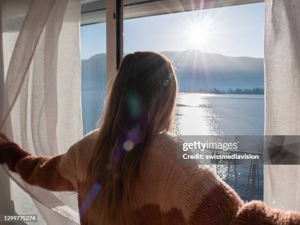 female opens curtains at sunrise, new beginning new day - balcony window stock pictures, royalty-free photos & images