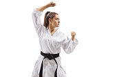 Young woman with black belt and kimono practicing karate kata