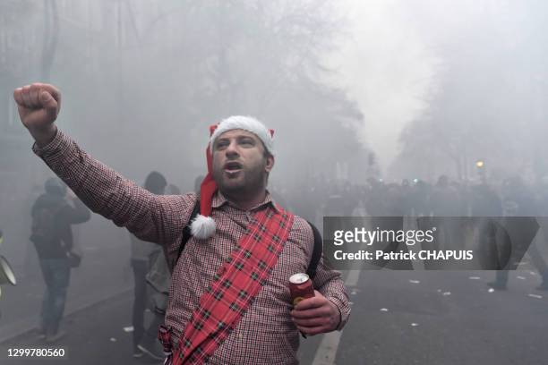Manifestant avec un bonnet de Père Noël le point en l'air et une canette de bière dans l'autre main lors de la manifestation contre le projet de...