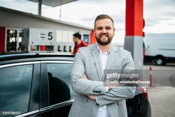 ガソリンスタンドに立って車を燃料に若いハンサムな大人の男と労働者。 - gas station ストックフォトと画像