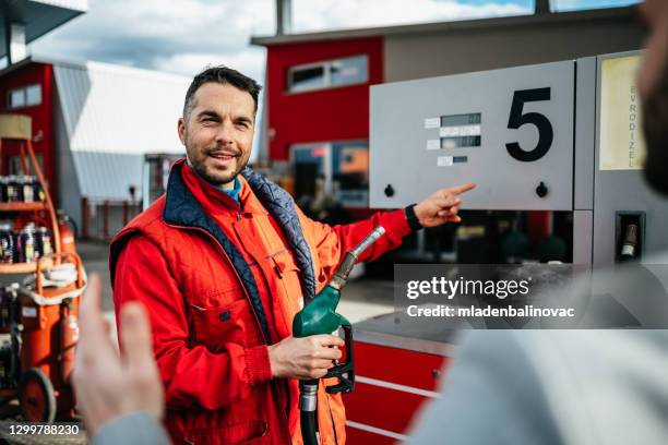 jonge knappe volwassen mens samen met arbeider die zich op benzinepost en het voeden auto bevindt. - working oil pumps stockfoto's en -beelden