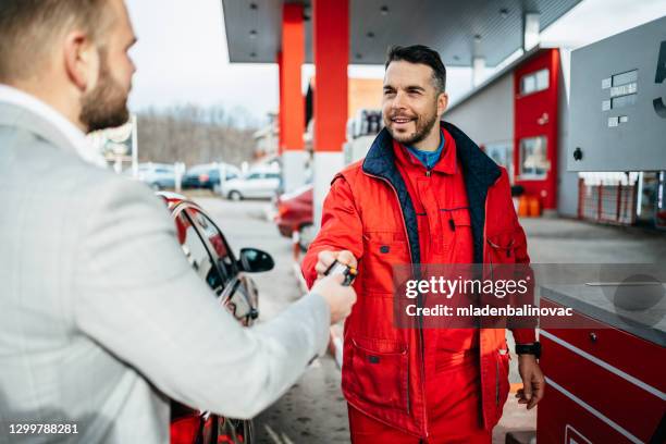 ガソリンスタンドで車に給油するための支払いを行うためにクレジットカードを使用して若い男。 - petrol paying ストックフォトと画像