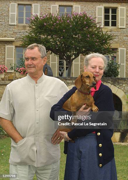 Queen Margrethe of Denmark holds her dog Celimen as her husband, Prince Henrik, stands beside her on the grounds of their Castle of Caix August 8,...