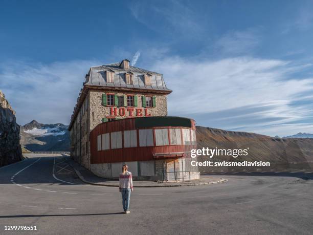 woman stands in front of the belvedere hotel on the furka pass - belvedere hotel stock pictures, royalty-free photos & images