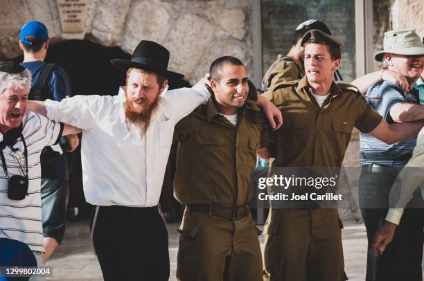 civilians and soldiers linking arms at the western wall in jerusalem - israeli people stock pictures, royalty-free photos & images