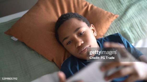 child boy playing on smartphone at home - boy bedroom stock pictures, royalty-free photos & images