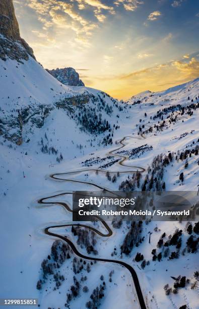 snowy mountain road at sunset, aerial view, passo gardena, dolomites - moutain sunset snow stock-fotos und bilder