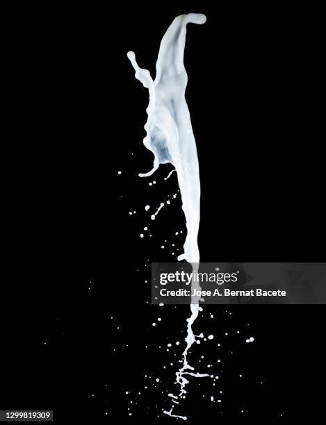 splashes, jet and drops of milk in motion suspended in the air on a black background. - milk wave stock pictures, royalty-free photos & images