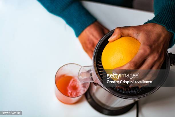 young woman making grapefruit juice. - juice extractor stock pictures, royalty-free photos & images