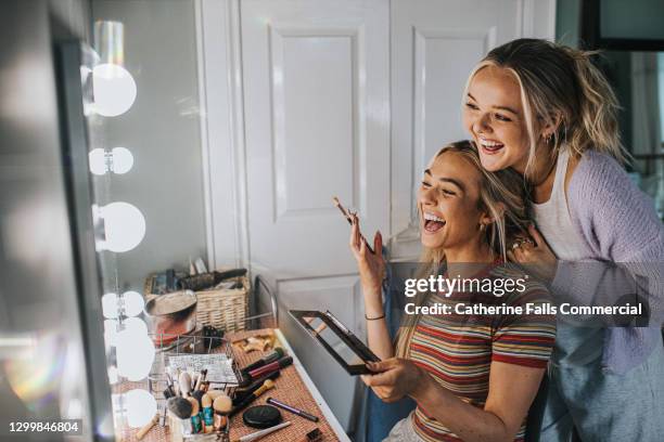 two young woman front of an illuminated mirror and apply make-up - up front party stock pictures, royalty-free photos & images