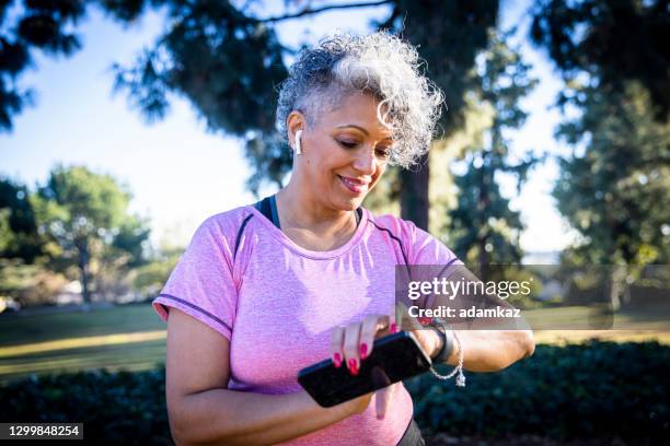 senior black woman running with a fitness tracker - fitnesstracker stock pictures, royalty-free photos & images