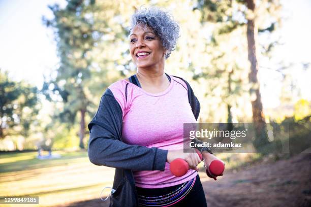 donna nera anziana che si allunga ed esercita con i pesi - esercizio fisico foto e immagini stock