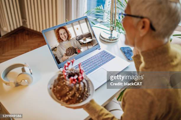 mujer madura está celebrando cumpleaños a través de videollamada en casa con su hija - cat with red hat fotografías e imágenes de stock