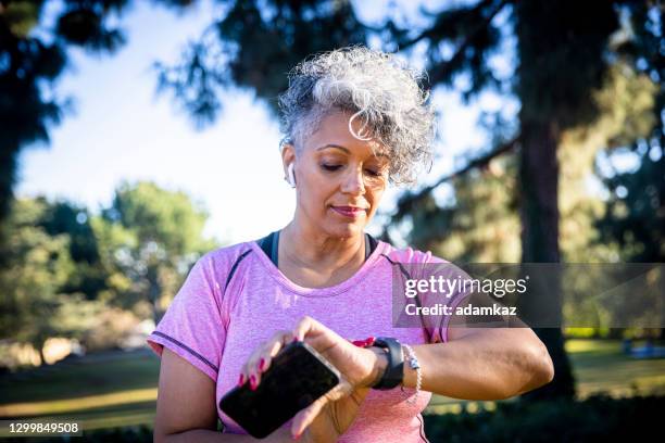 senior black woman running with a fitness tracker - smart watch stock pictures, royalty-free photos & images